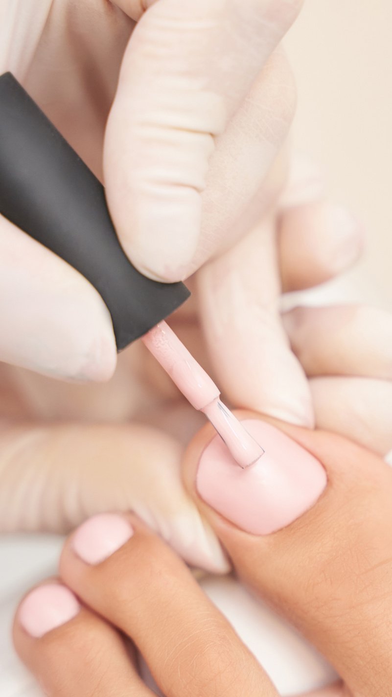 Hand Applying Pink Nail Polish on Toenails